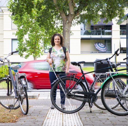 Vrouw loopt op geleidelijn tegen een fiets