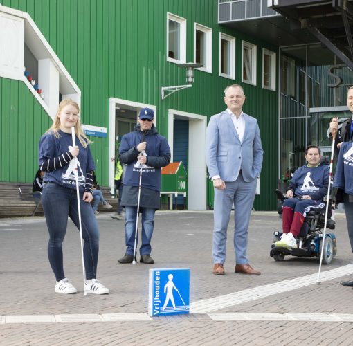 Groep mensen staat bij de Houd de lijn vrij stoeptegel